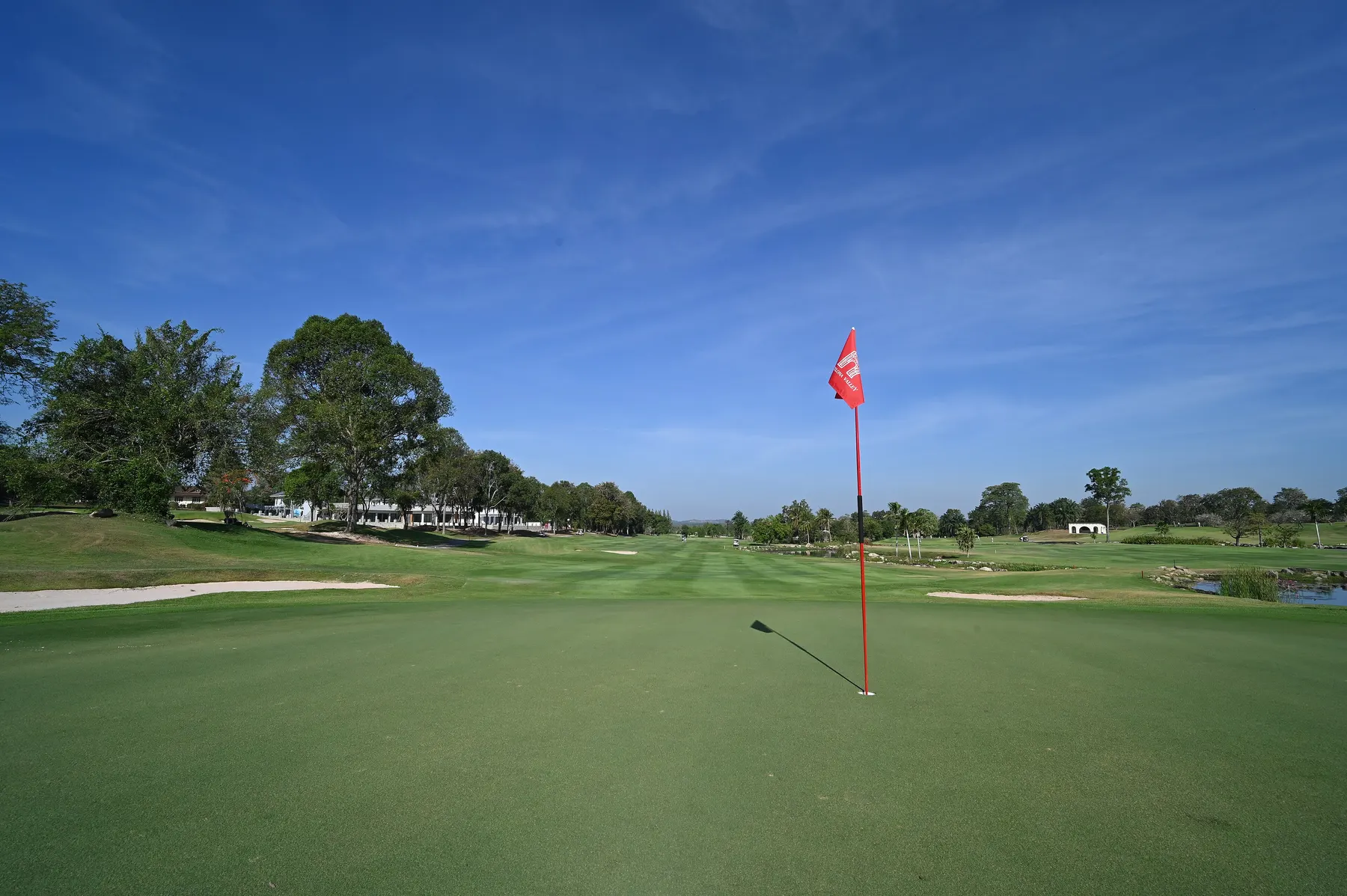 Flag on an immaculate golf green under a clear sky