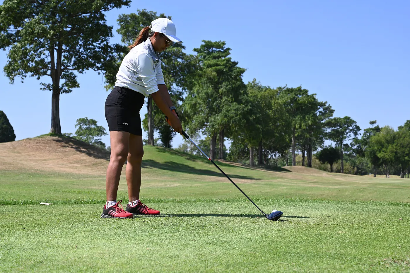 Golfer lining up a tee shot on a sunny fairway